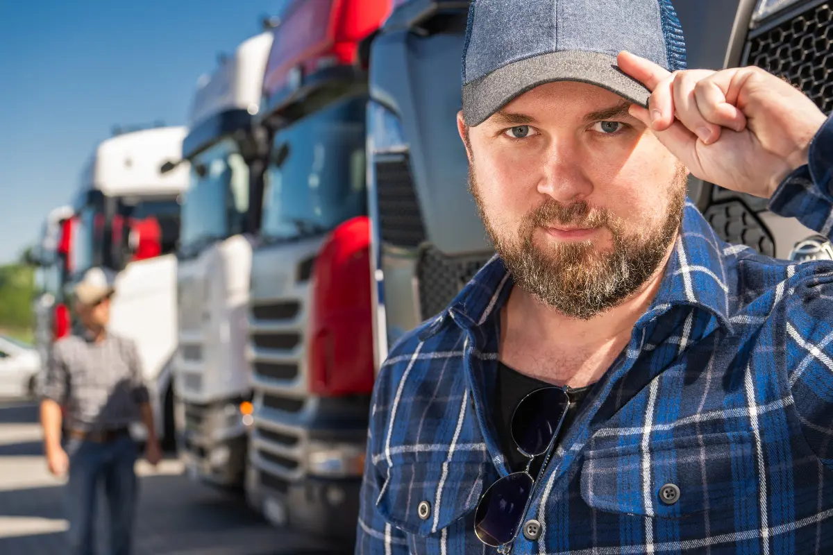Commercial truck driver standing beside fleet vehicles before a compliance review